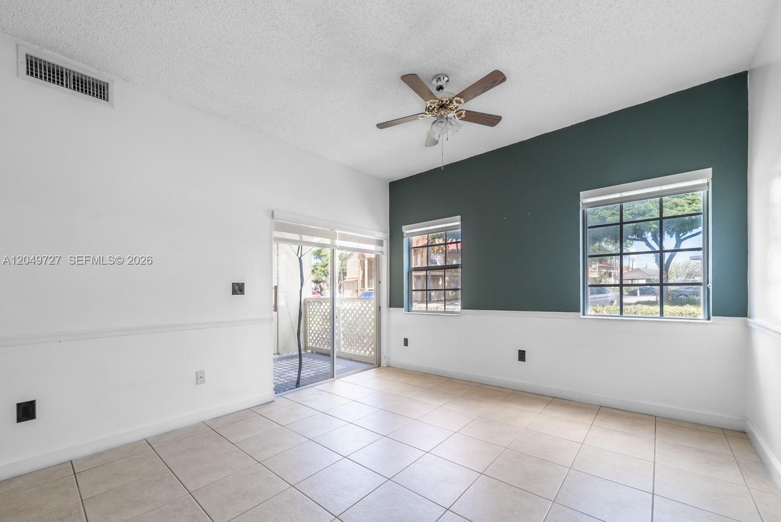 A room with tile flooring, a ceiling fan, white walls, and a dark green accent wall — 18308 NW 68th Ave # B, Hialeah FL 33015, HIALEAH, FL