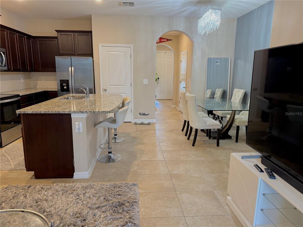 A kitchen with dark cabinets and a granite island opens to a dining area — 6549 SERENITY FALL LANE, SARASOTA, FL