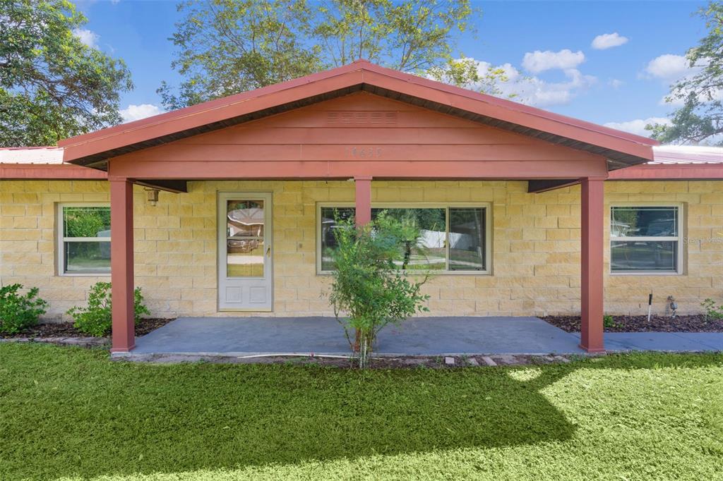 A single-story house with a stone facade, a covered front porch, and a metal roof — 14635 SE 28TH COURT, SUMMERFIELD, FL