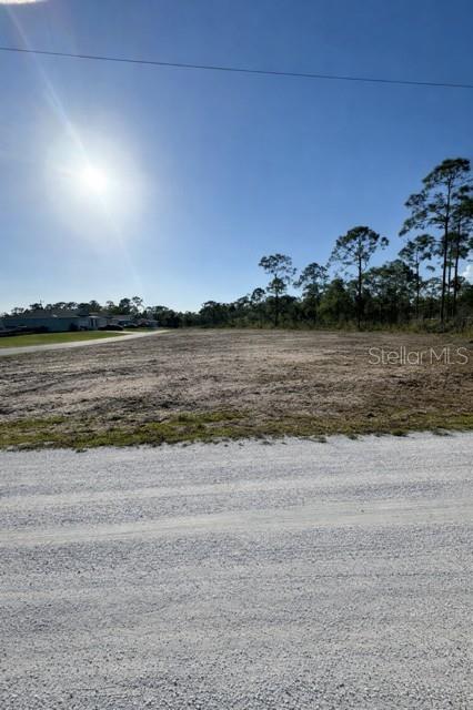 A vacant, cleared lot of land sits next to a gravel road under a sunny sky — 12359 LOS OLAS DRIVE, PUNTA GORDA, FL