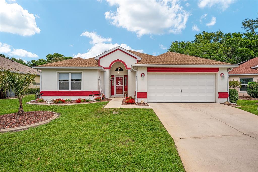 A single-story house with a white stucco exterior, red trim, and a two-car garage — 6795 SW 114TH STREET ROAD, OCALA, FL