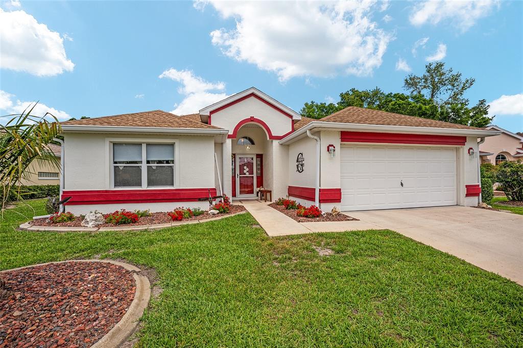A single-story house with a white stucco exterior, red trim, and a two-car garage — 6795 SW 114TH STREET ROAD, OCALA, FL