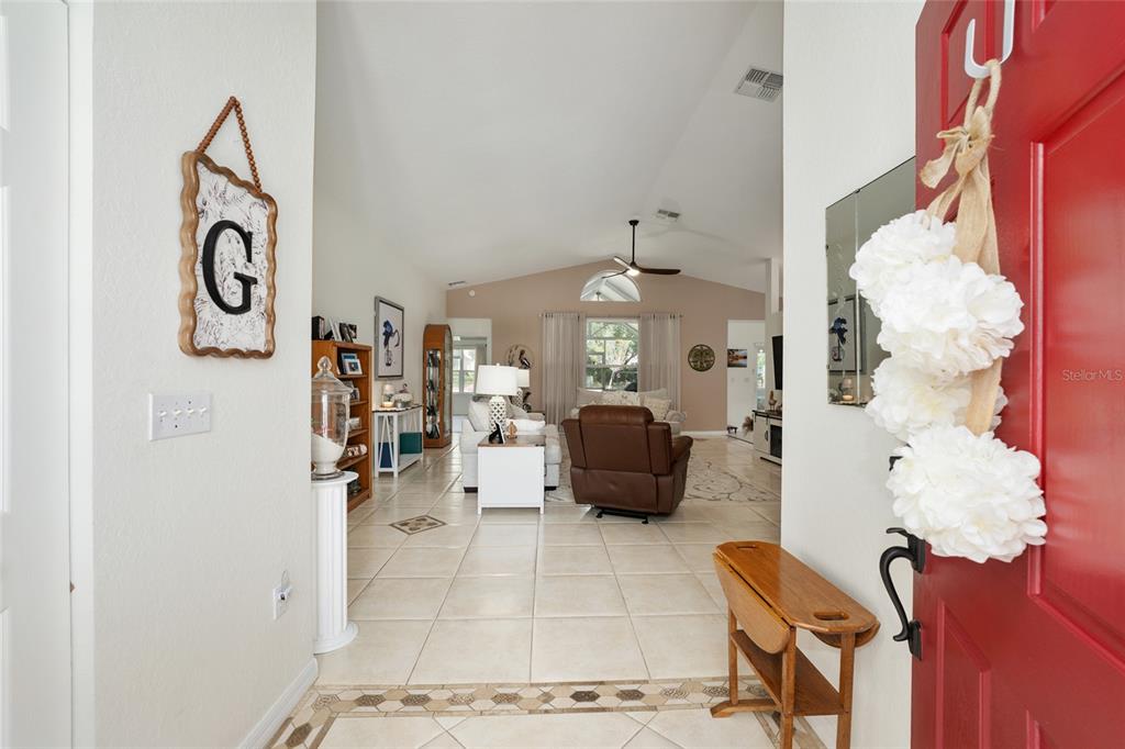 A view from an entryway into a living room with tiled floors and vaulted ceilings — 6795 SW 114TH STREET ROAD, OCALA, FL