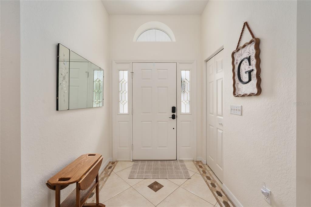 An entryway features a white front door with sidelights, tiled flooring, and a wall mirror — 6795 SW 114TH STREET ROAD, OCALA, FL