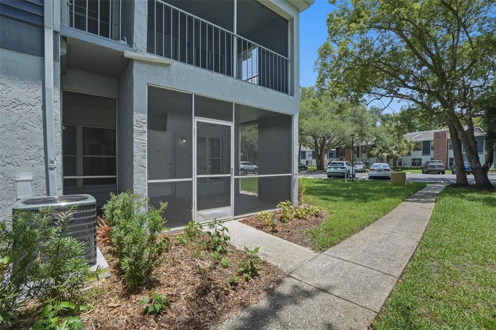 A ground-level apartment exterior features a screened-in patio, an air conditioning unit, and landscaping — 2402 NORTHLAKE DRIVE UNIT 2402, SANFORD, FL