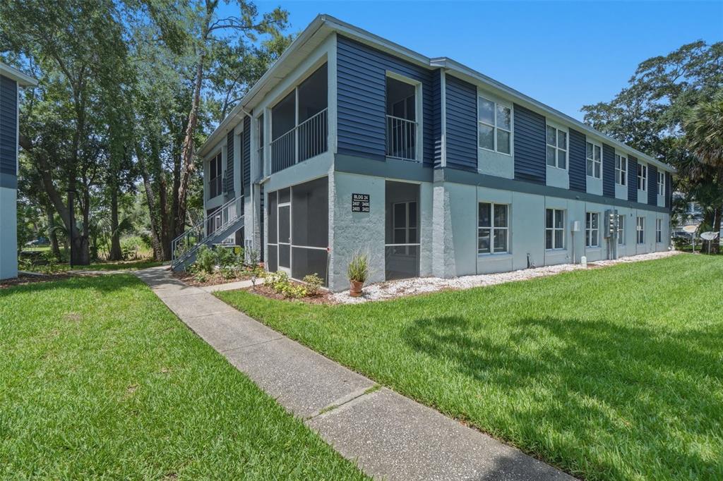 A two-story apartment building with blue siding, screened balconies, and a concrete walkway — 2402 NORTHLAKE DRIVE UNIT 2402, SANFORD, FL