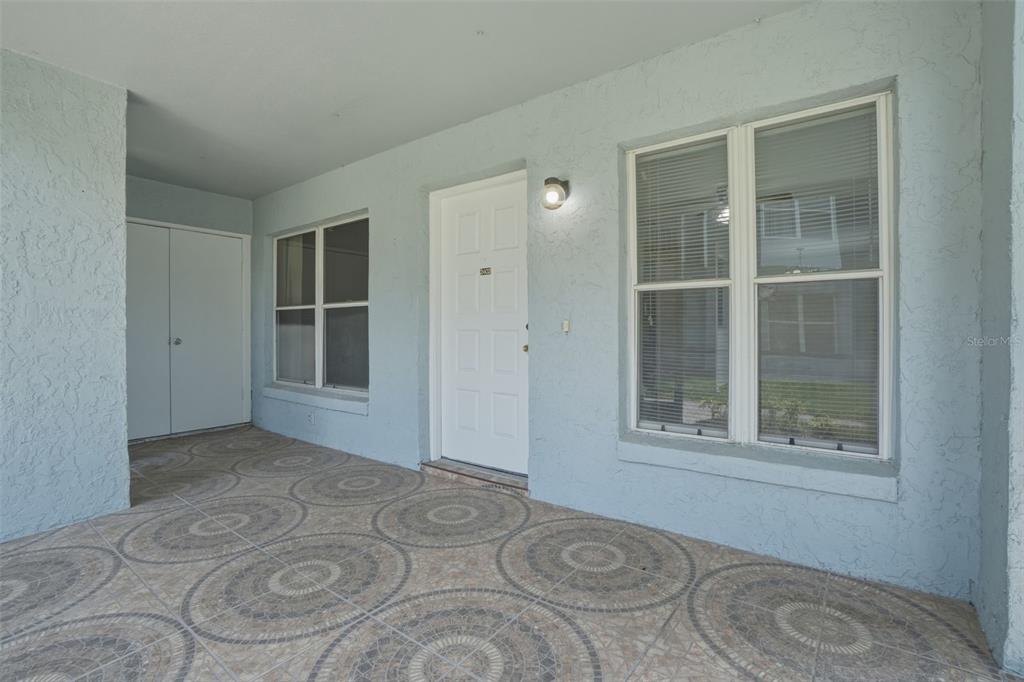 A covered porch features light blue stucco walls, a white front door, and patterned tile flooring — 2402 NORTHLAKE DRIVE UNIT 2402, SANFORD, FL
