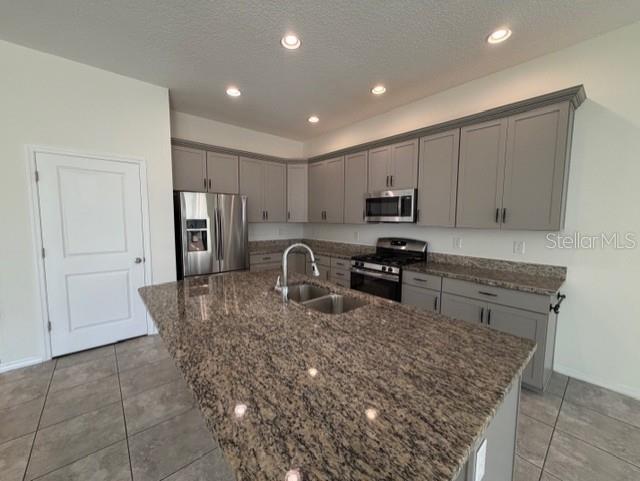 A kitchen features gray cabinets, granite countertops, a large island, and stainless steel appliances — 998 GRAND HILLTOP, APOPKA, FL