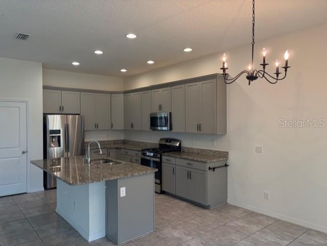 A kitchen features gray cabinets, granite countertops, a center island, and a hanging chandelier — 998 GRAND HILLTOP, APOPKA, FL