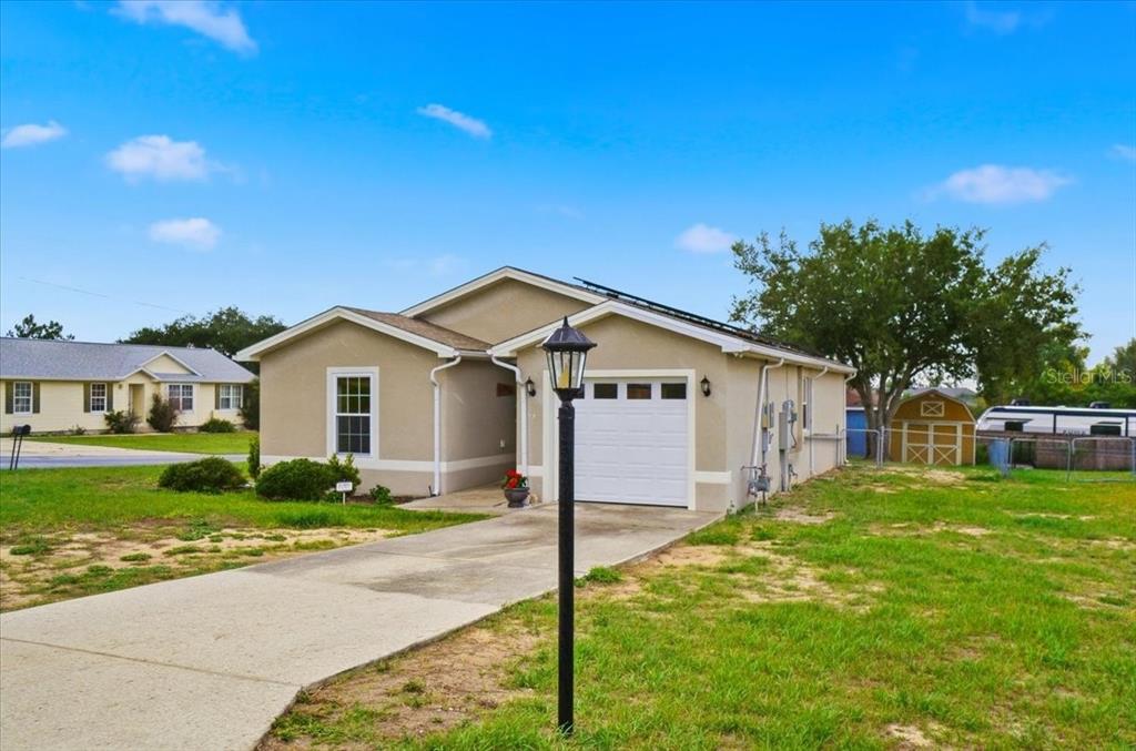 A single-story house with a white garage door, tan stucco exterior, and a concrete driveway — 115 SEMINOLE ROAD, BABSON PARK, FL