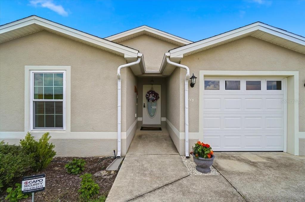A single-story house exterior features a beige stucco facade, a garage, and a front entrance — 115 SEMINOLE ROAD, BABSON PARK, FL