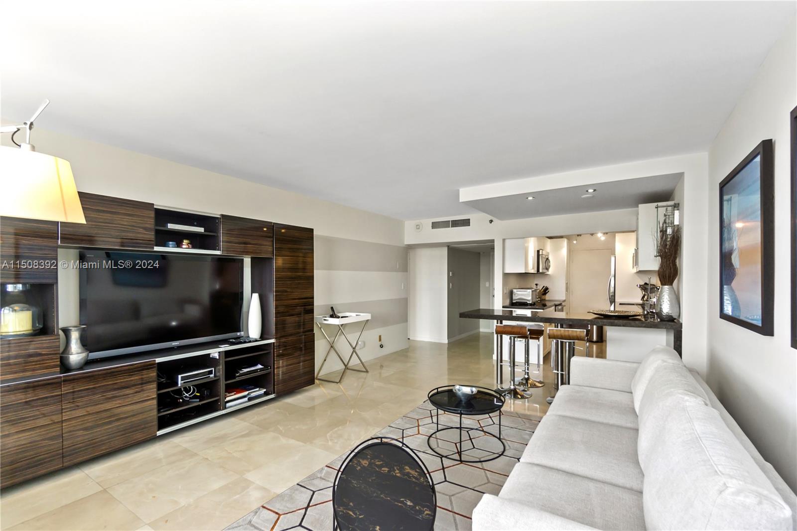 A living room features a large media unit, a sofa, and an open kitchen area — 100 Lincoln Rd # 1202, Miami Beach FL 33139, MIAMI BEACH, FL