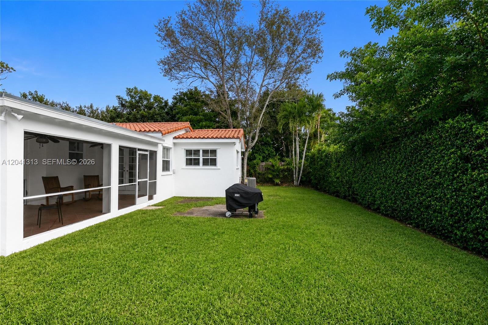 A backyard features a white house with a screened patio, tiled roof, and a grill — 5760 SW 51st St # 0, Miami FL 33155, MIAMI, FL