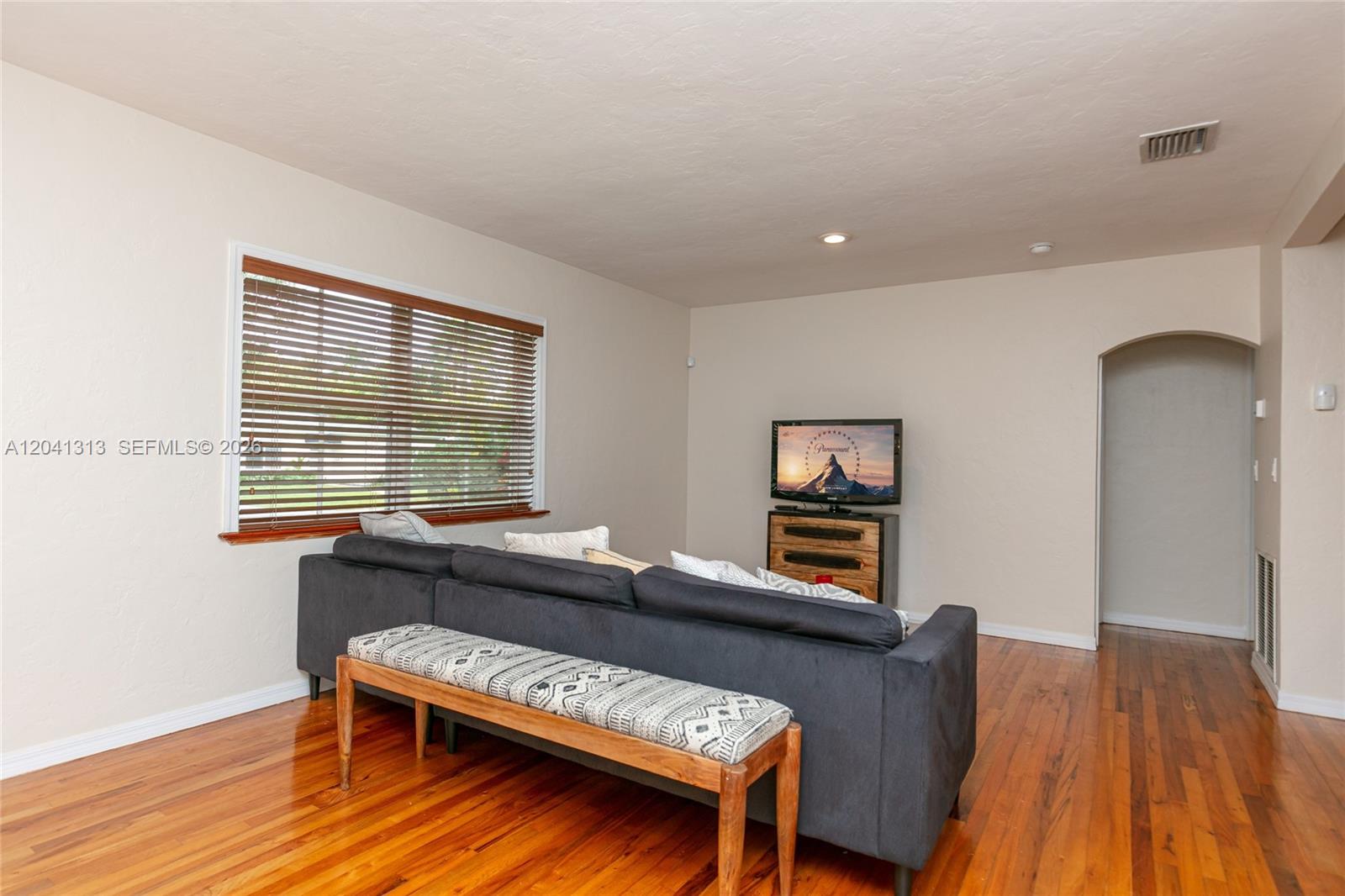 A living room features a dark sofa, a patterned bench, and a television on a stand — 5760 SW 51st St # 0, Miami FL 33155, MIAMI, FL
