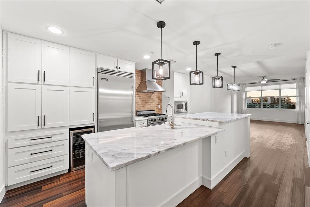 A modern kitchen features white cabinetry, a marble-topped island, stainless steel appliances, and brick accents — 1208 E KENNEDY BOULEVARD UNIT 618, TAMPA, FL