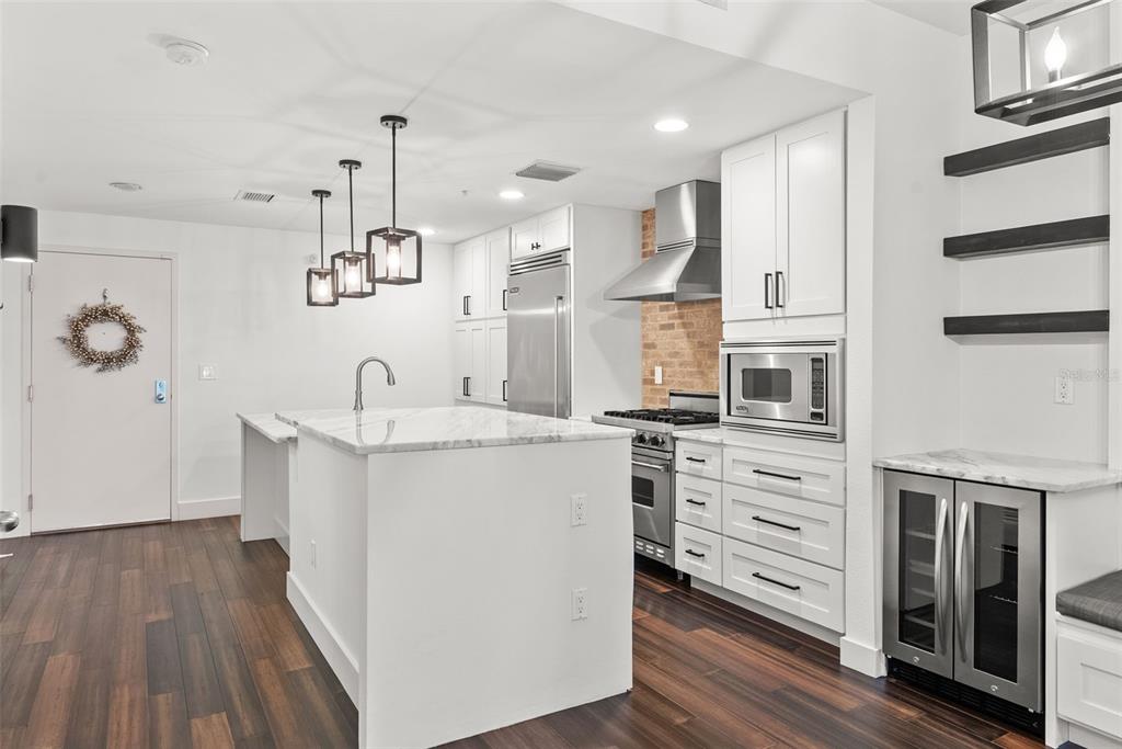 A modern kitchen features white cabinetry, a marble-topped island, stainless steel appliances, and dark flooring — 1208 E KENNEDY BOULEVARD UNIT 618, TAMPA, FL