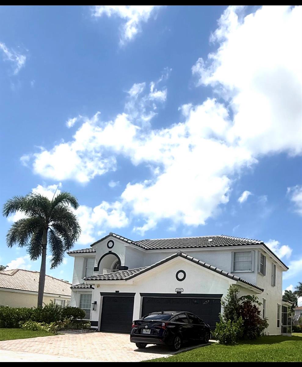 A two-story house with white stucco walls, a dark tile roof, and a black car — 22057 Palm Grass Drive, Boca Raton FL 33428, BOCA RATON, FL