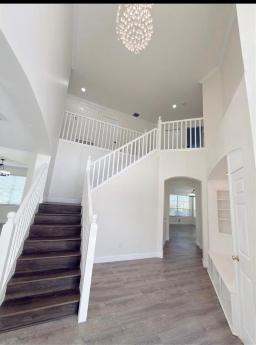 A bright two-story foyer features a dark wood staircase, white railings, and a crystal chandelier — 22057 Palm Grass Drive, Boca Raton FL 33428, BOCA RATON, FL