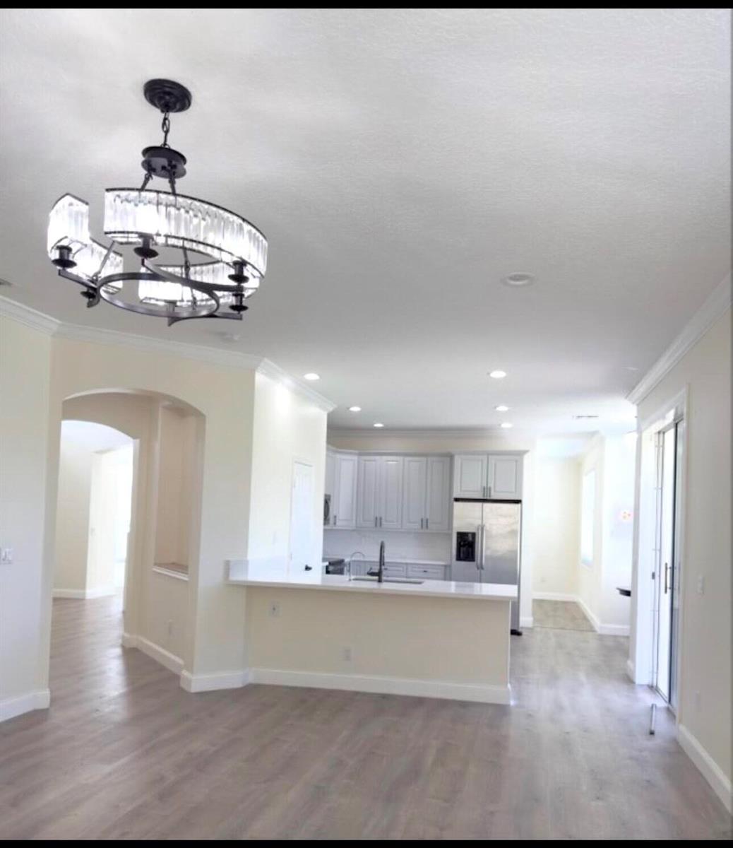 A kitchen with light-colored cabinets and a breakfast bar overlooks an open-concept living area — 22057 Palm Grass Drive, Boca Raton FL 33428, BOCA RATON, FL