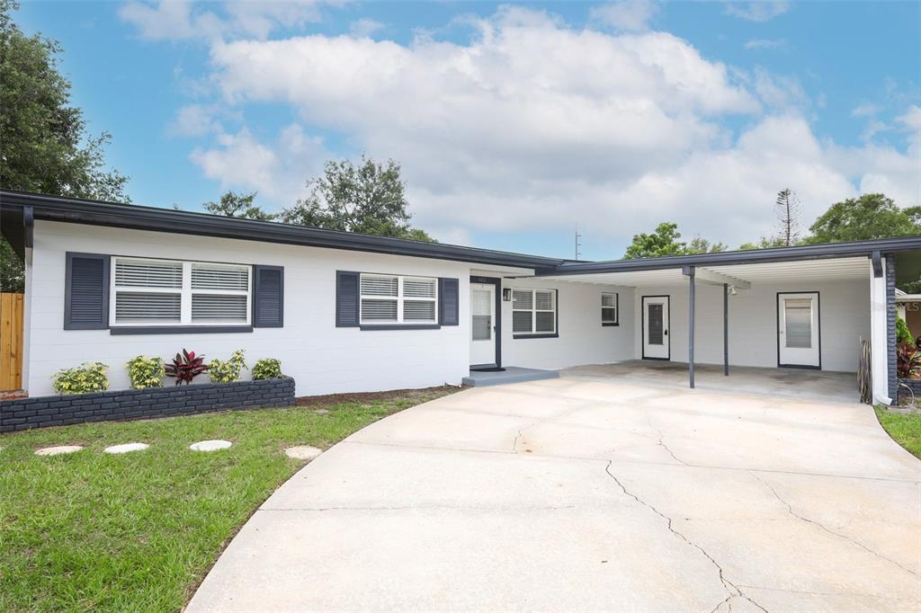 A single-story white house with dark shutters and a covered carport over a concrete driveway — 4422 GILPIN WAY, ORLANDO, FL