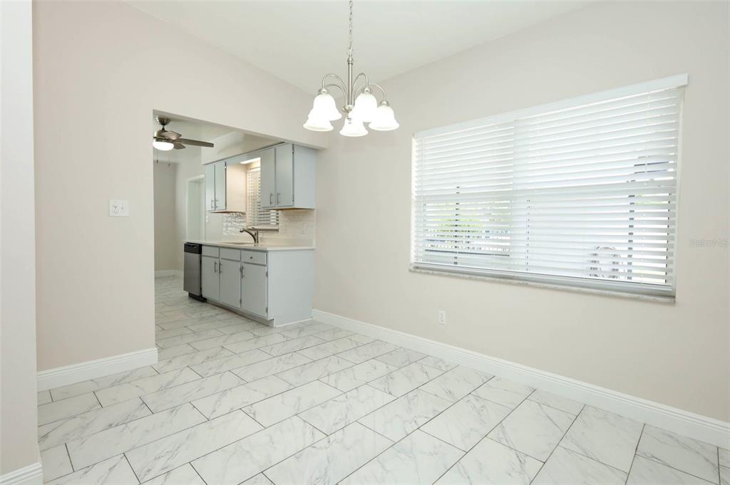 A dining area with white marble-look tile floors leads into a kitchen with light-colored cabinets — 4422 GILPIN WAY, ORLANDO, FL