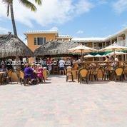 An outdoor patio area features a tiki bar with thatched roofs and umbrella-covered seating — N Surf Rd, Hollywood FL 33019, HOLLYWOOD, FL