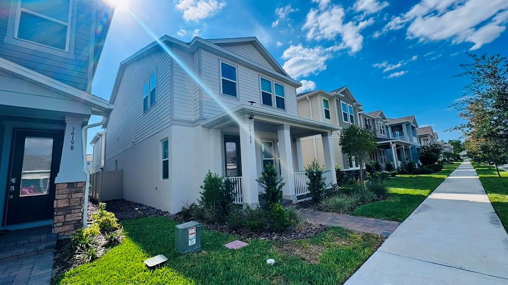 A row of two-story suburban houses with light-colored siding and front porches lines a sidewalk — 16192 HONEY HARVEST STREET, WINTER GARDEN, FL