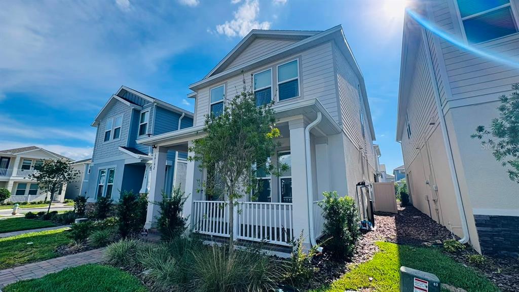 A two-story house with light siding and a front porch sits between neighboring homes — 16192 HONEY HARVEST STREET, WINTER GARDEN, FL