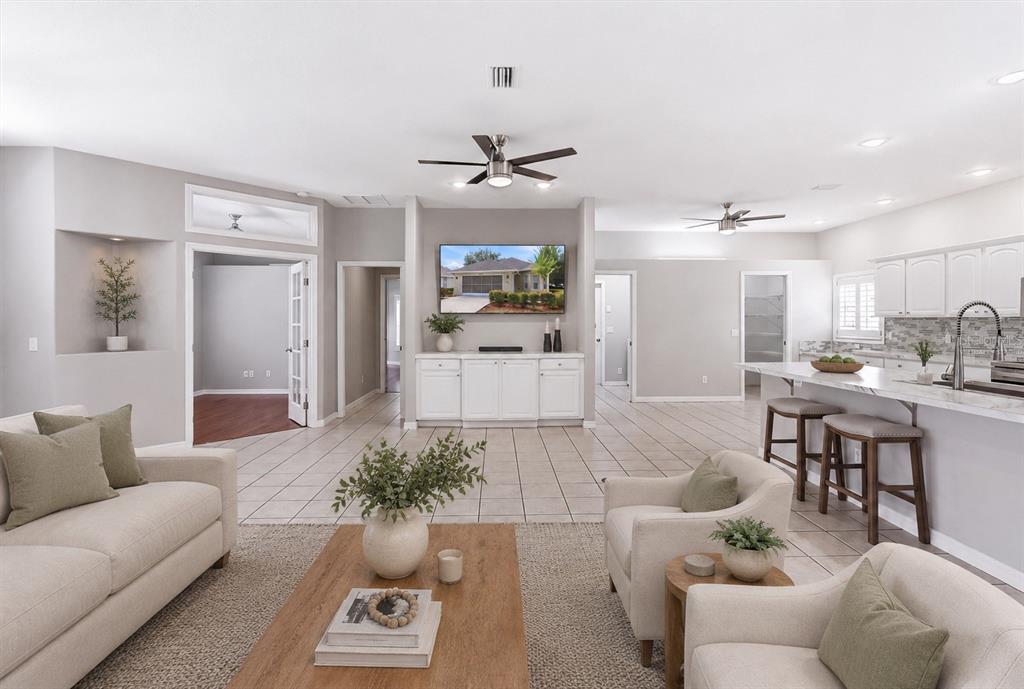 An open-concept living room features tile flooring, a central television, and an adjacent kitchen island — 6484 W CANNONDALE DRIVE, CRYSTAL RIVER, FL