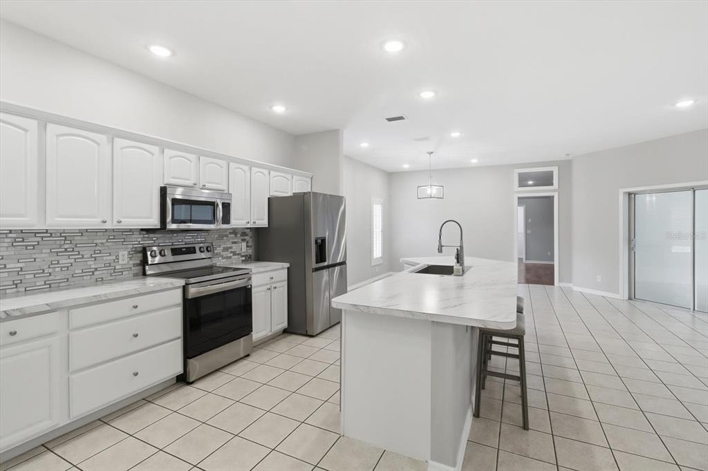 A kitchen features white cabinets, stainless steel appliances, a marble-look island, and tile flooring — 6484 W CANNONDALE DRIVE, CRYSTAL RIVER, FL