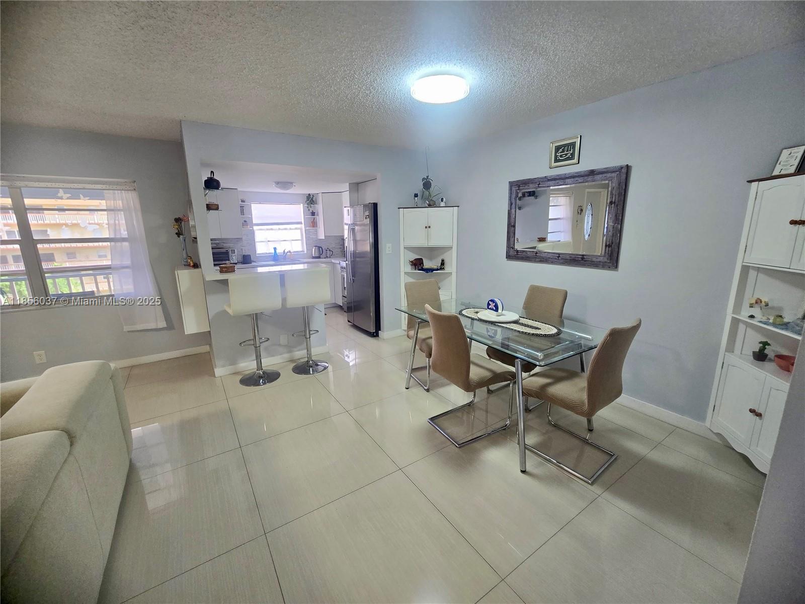 A dining area with a glass table and chairs sits adjacent to a kitchen counter — 5300 Washington St # U403, Hollywood FL 33021, HOLLYWOOD, FL