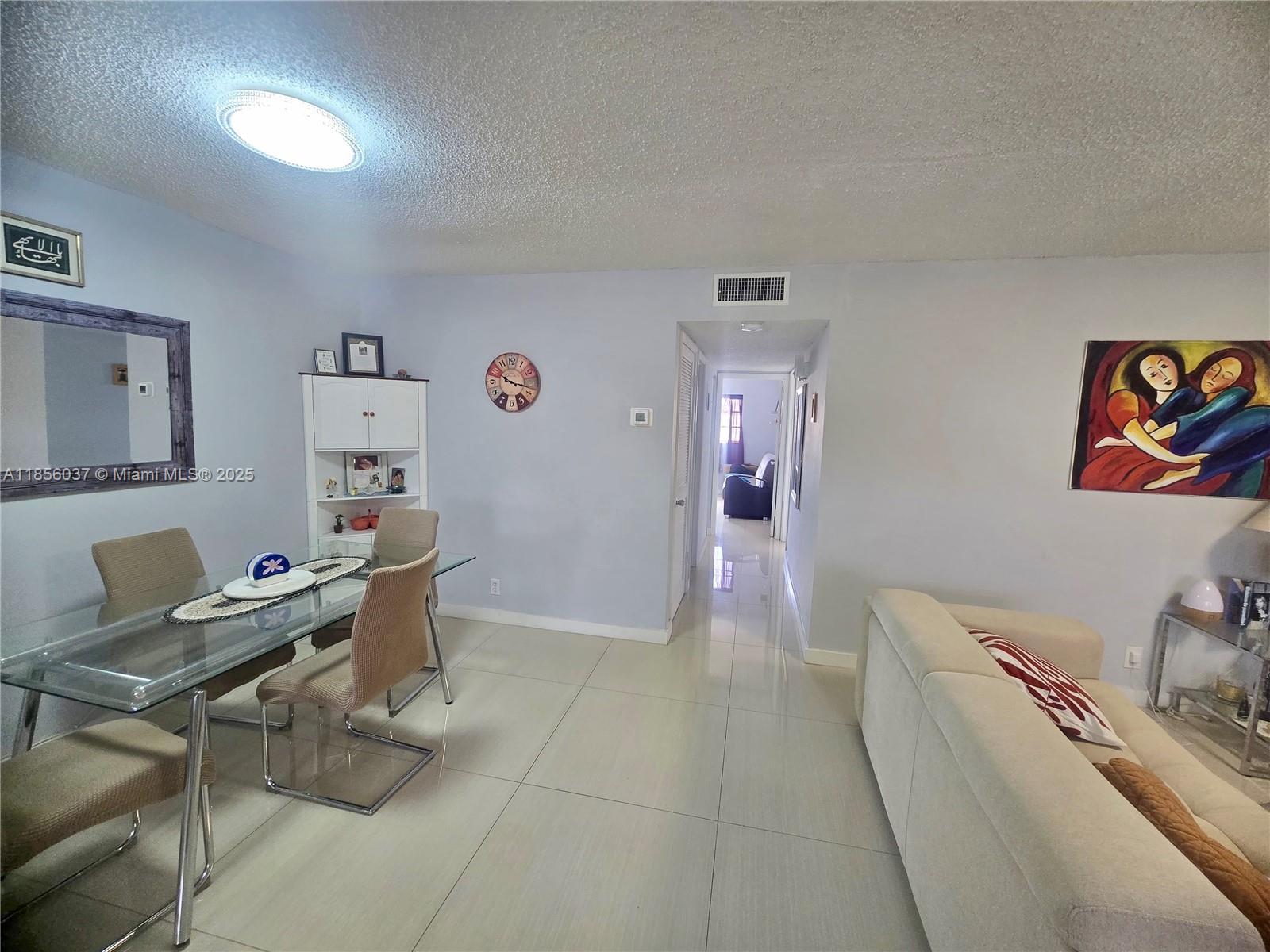 A dining area with a glass table and a living room with a beige sofa — 5300 Washington St # U403, Hollywood FL 33021, HOLLYWOOD, FL