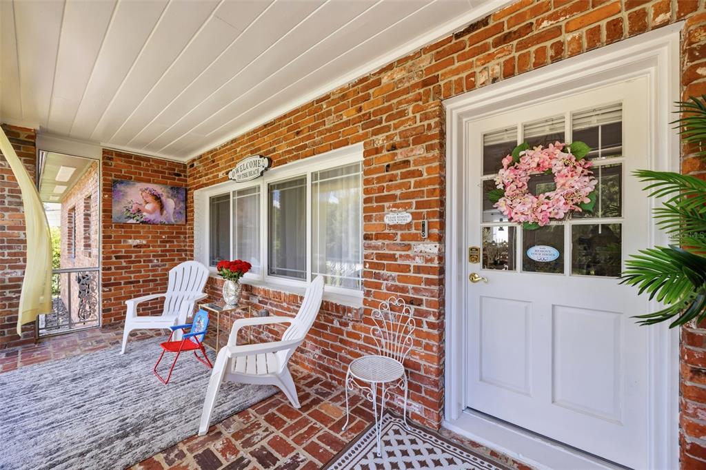 A covered brick porch features white chairs, a front door with a wreath, and windows — 508 ALTA VISTA DRIVE, HAINES CITY, FL