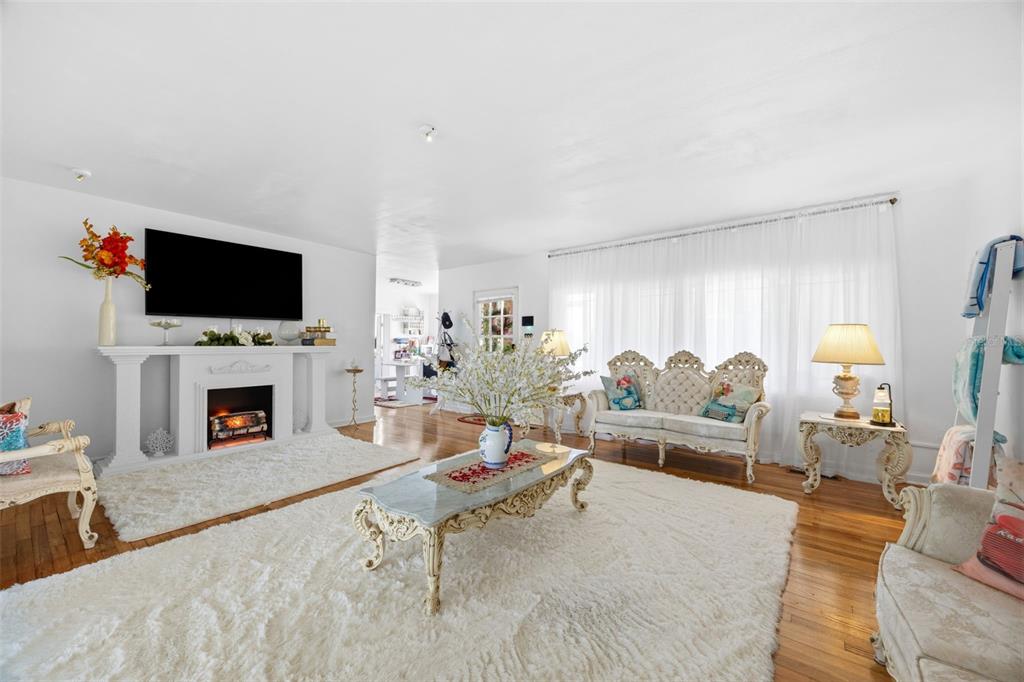 A bright living room features a fireplace, white shag rugs, and ornate vintage-style furniture — 508 ALTA VISTA DRIVE, HAINES CITY, FL