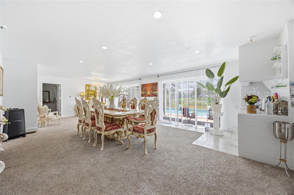 A dining room features a formal table set, carpeted flooring, and sliding glass doors to a pool — 508 ALTA VISTA DRIVE, HAINES CITY, FL