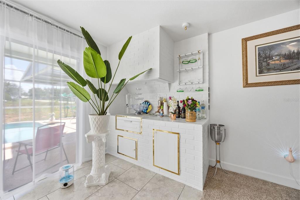 A white brick wet bar with gold trim stands next to a large potted plant — 508 ALTA VISTA DRIVE, HAINES CITY, FL