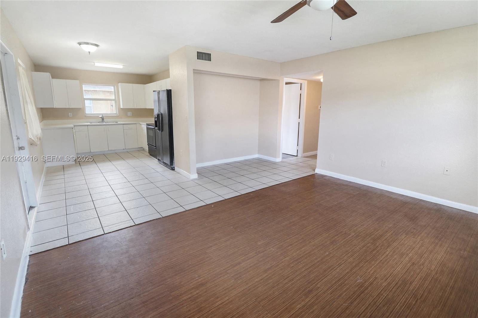 An open-concept living area features wood-look flooring, a tiled kitchen, and a ceiling fan — 2725 NW 3rd St, Pompano Beach FL 33069, POMPANO BEACH, FL