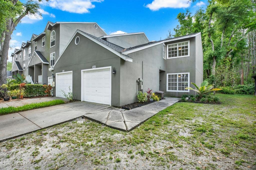 A gray two-story townhouse with a white garage door and a concrete walkway — 5844 RED CEDAR LANE, TAMPA, FL