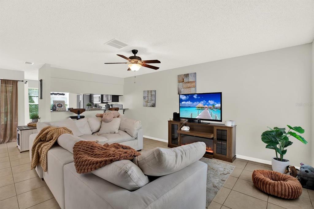 A living room features a sectional sofa, a television on a media console, and tile flooring — 5844 RED CEDAR LANE, TAMPA, FL