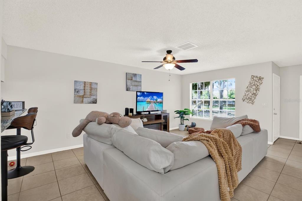 A living room features a large sectional sofa, a television on a stand, and tile flooring — 5844 RED CEDAR LANE, TAMPA, FL