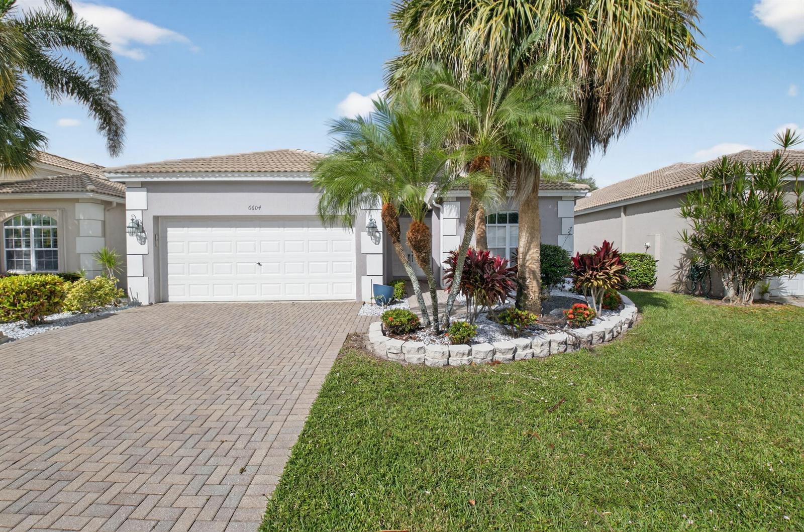 A single-story house with a paved driveway, a two-car garage, and a landscaped front yard — 6604 Southport Drive, Boynton Beach FL 33472, BOYNTON BEACH, FL