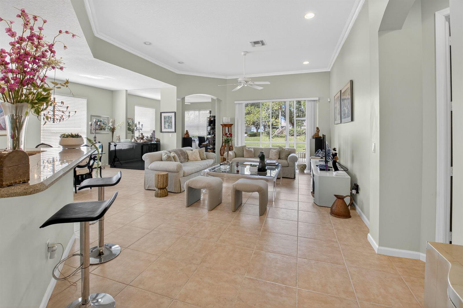 A spacious living room with tile floors, a glass coffee table, and large sliding glass doors — 6604 Southport Drive, Boynton Beach FL 33472, BOYNTON BEACH, FL