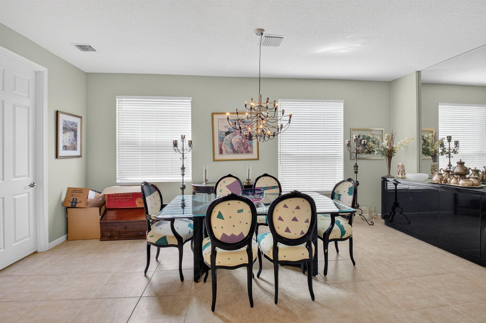 A dining room features a glass-top table, patterned chairs, a chandelier, and tile flooring — 6604 Southport Drive, Boynton Beach FL 33472, BOYNTON BEACH, FL
