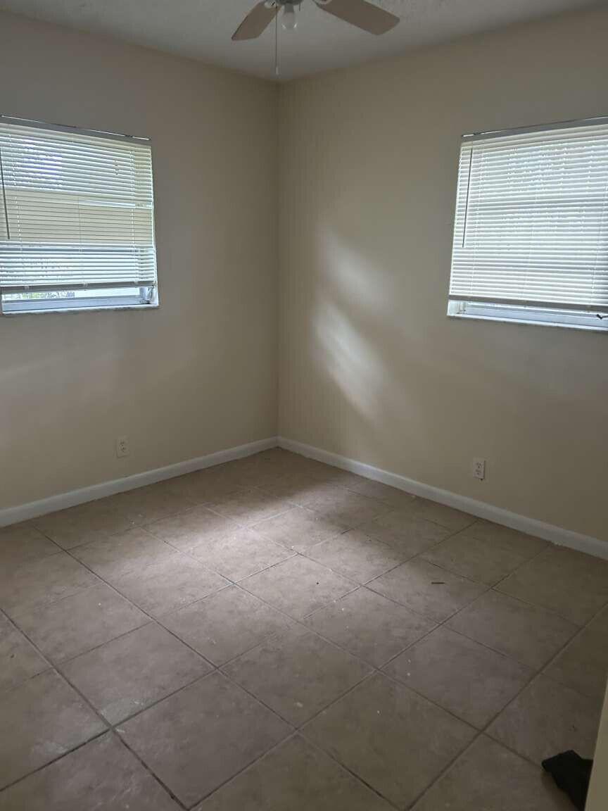 An empty bedroom features beige walls, tile flooring, two windows with blinds, and a ceiling fan — 3370 NW 8th Place, Lauderhill FL 33311, LAUDERHILL, FL