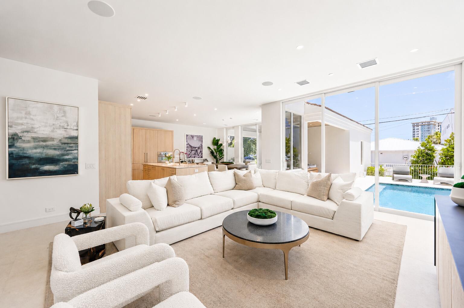 A modern living room with a white sectional sofa, round coffee table, and pool view — 519 SE 4th Avenue, Delray Beach FL 33483, DELRAY BEACH, FL