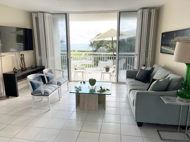 A living room with tile floors, a sofa, two chairs, and a balcony overlooking the ocean — 2780 S Ocean Boulevard # 312, Palm Beach FL 33480, PALM BEACH, FL