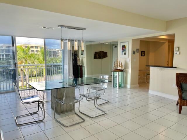 A dining area with a glass table, clear chairs, and a view of palm trees — 2780 S Ocean Boulevard # 312, Palm Beach FL 33480, PALM BEACH, FL
