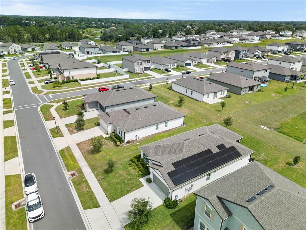 An aerial view shows a suburban neighborhood with single-family homes and a solar-paneled roof — 1313 STERLING POINTE DRIVE, DELTONA, FL
