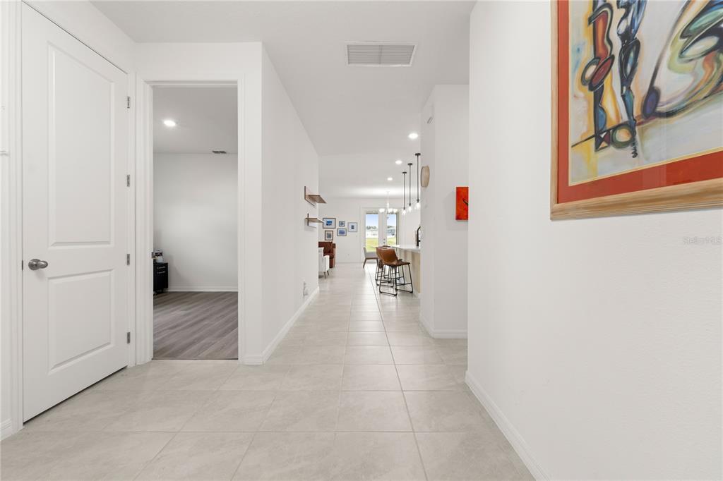 A tiled hallway leads from a white door toward an open-concept kitchen and living area — 1313 STERLING POINTE DRIVE, DELTONA, FL