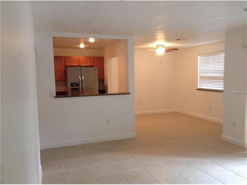 A view of a living area with tile flooring looking into a kitchen with wood cabinets — 3975 VERSAILLES DRIVE UNIT 3975F, ORLANDO, FL